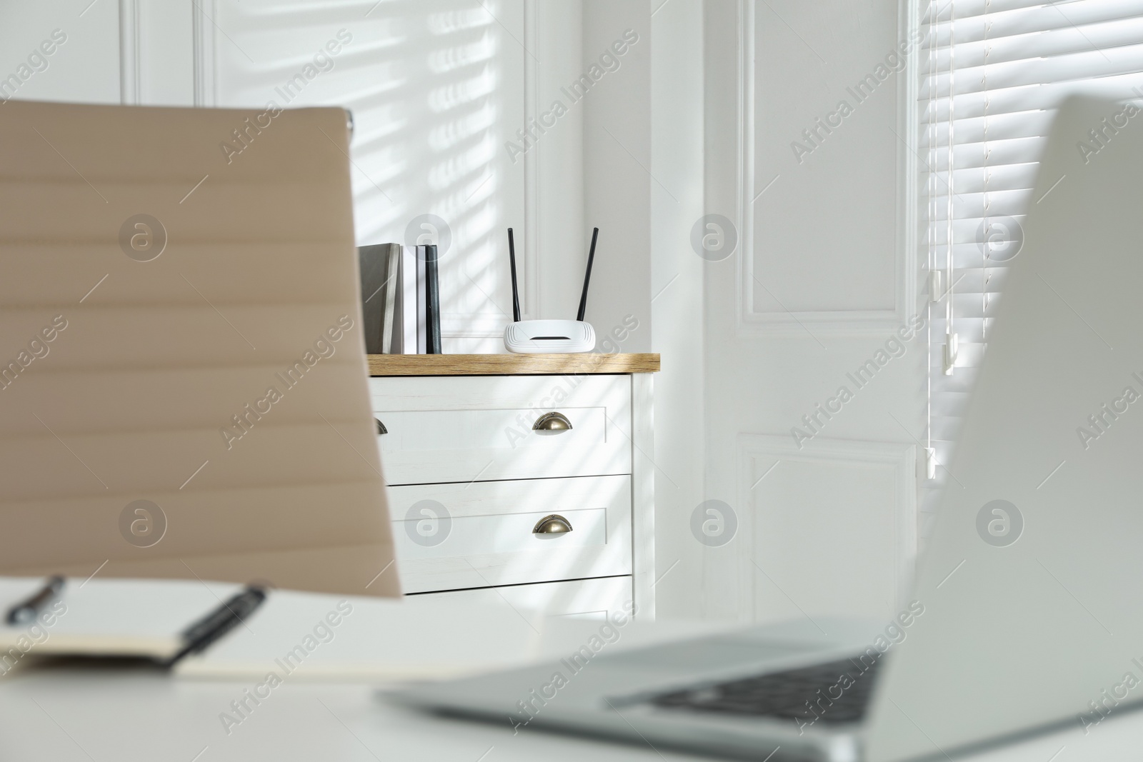 Photo of Modern wi-fi router on chest of drawers indoors