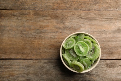 Photo of Bowl of dried kiwi on wooden background, top view with space for text. Tasty and healthy fruit