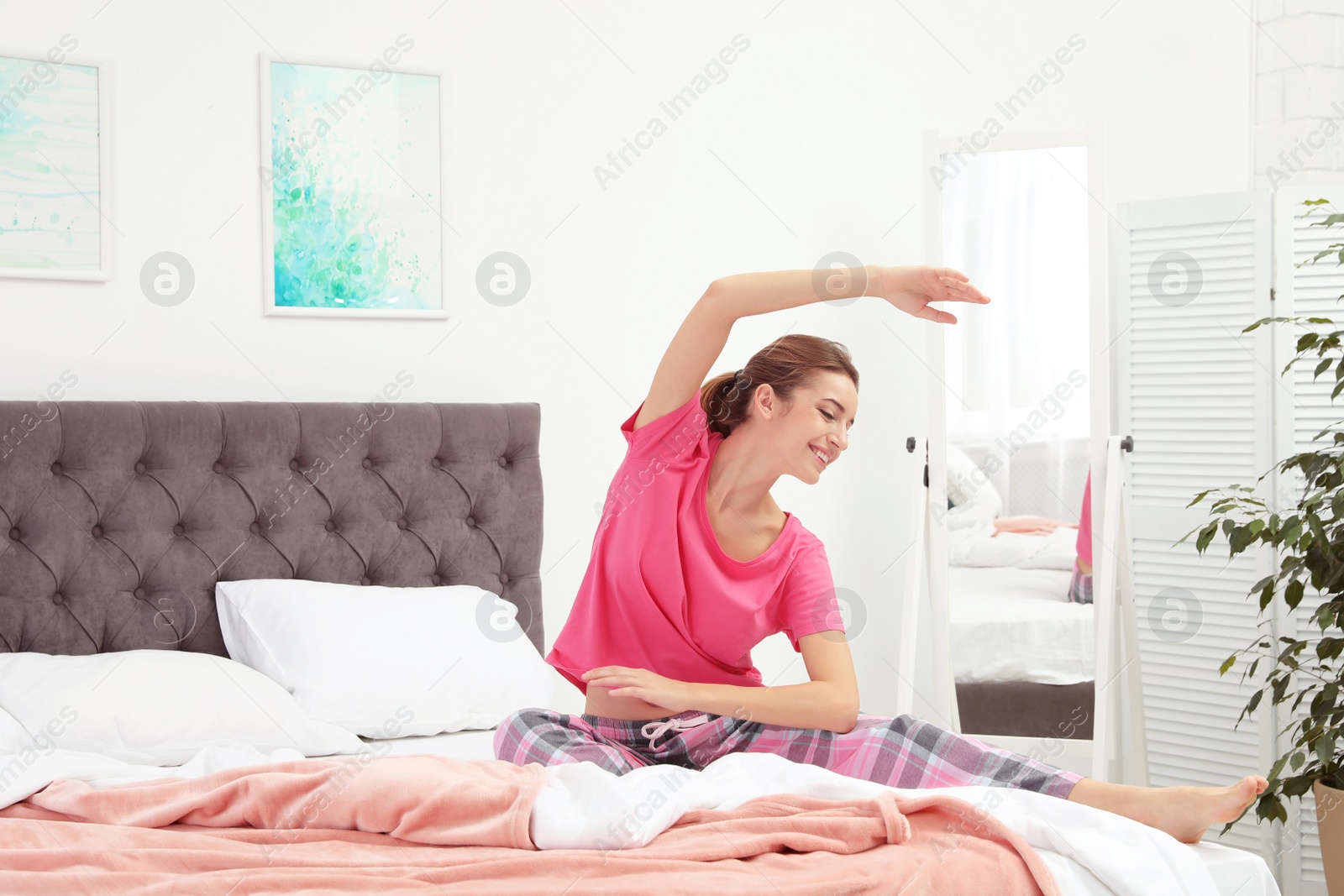 Photo of Young beautiful woman doing exercise on bed at home. Morning fitness