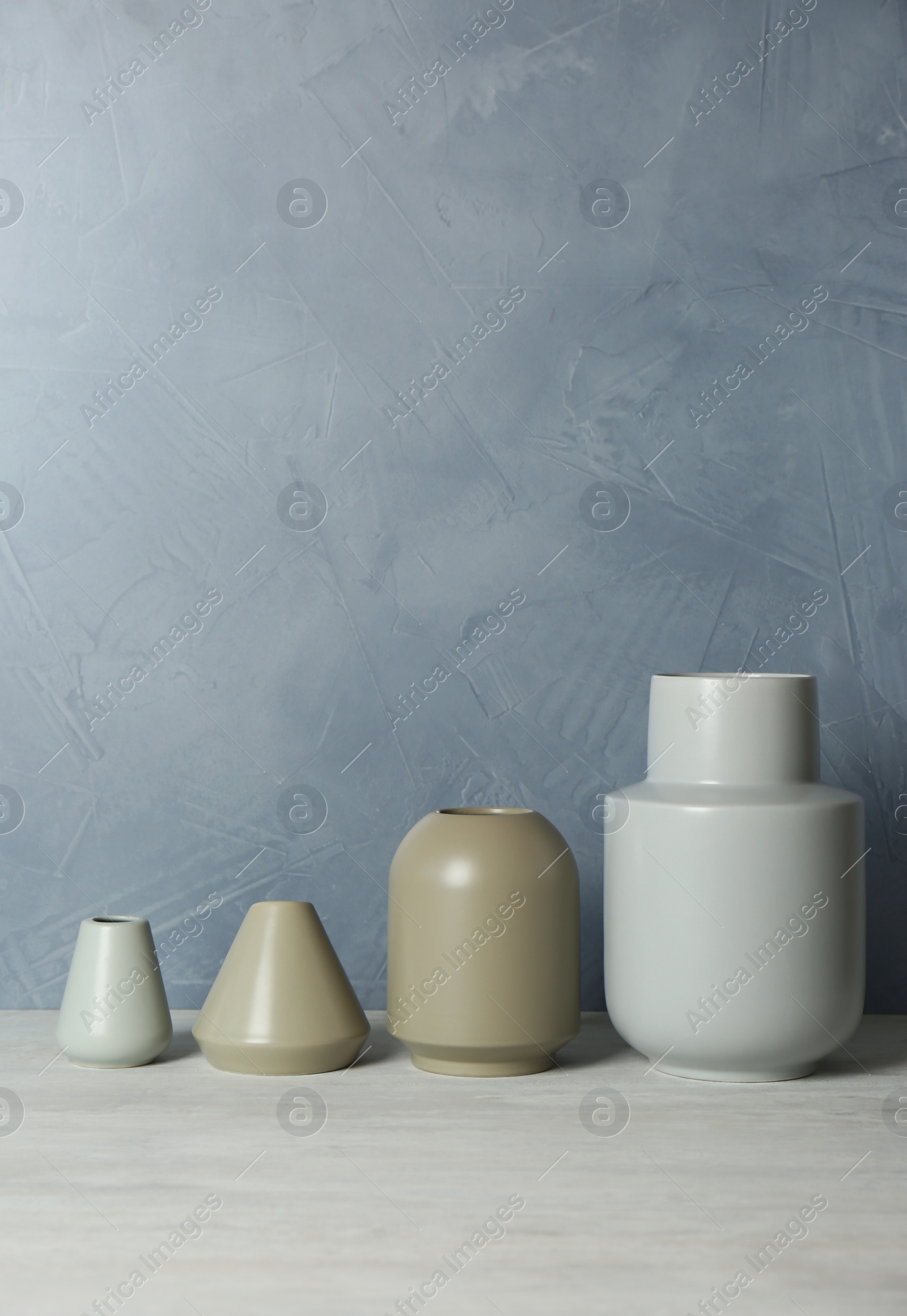 Photo of Beautiful ceramic vases on table against color wall. Space for text