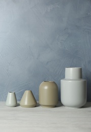 Beautiful ceramic vases on table against color wall. Space for text