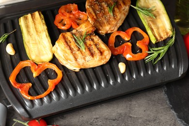 Photo of Electric grill with tasty meat, spices and vegetables on grey table