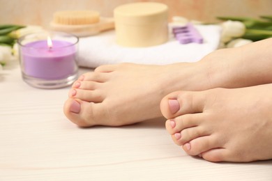 Photo of Woman with neat toenails after pedicure procedure on wooden floor, closeup