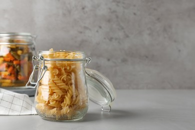 Photo of Pasta in glass jars on grey table, space for text