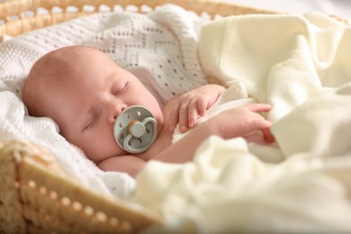 Cute newborn baby sleeping on white blanket in wicker crib, closeup