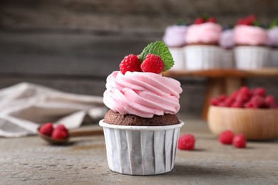 Photo of Sweet cupcake with fresh raspberries on wooden table