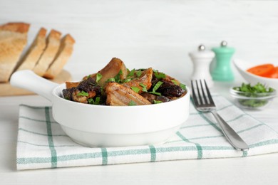 Photo of Tasty fried cracklings with parsley on white wooden table. Cooked pork lard