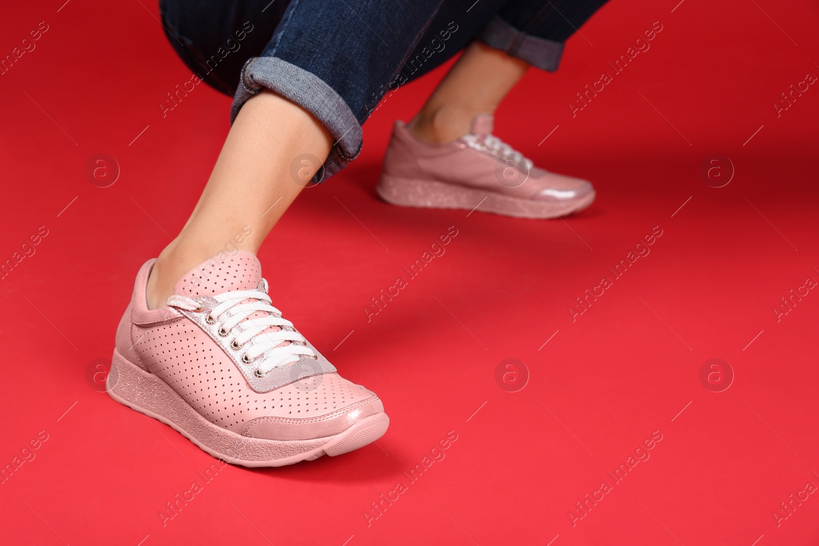 Photo of Woman in stylish sport shoes on color background