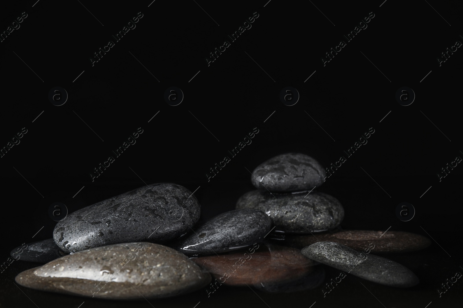 Photo of Stones in water on black background, space for text. Zen lifestyle