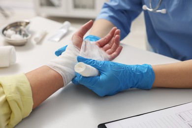 Photo of Doctor bandaging patient's burned hand in hospital, closeup