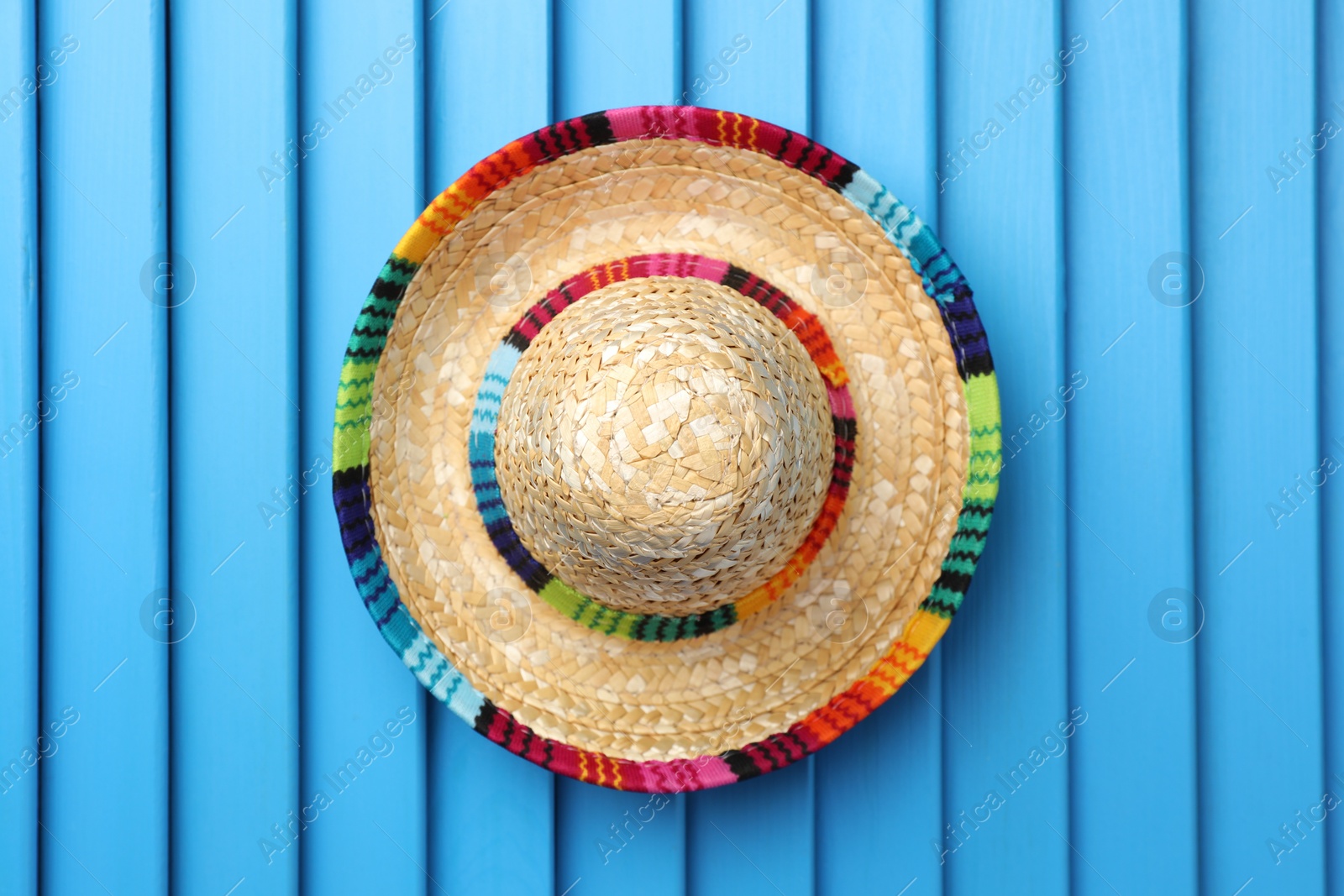 Photo of Mexican sombrero hat on blue wooden surface, top view