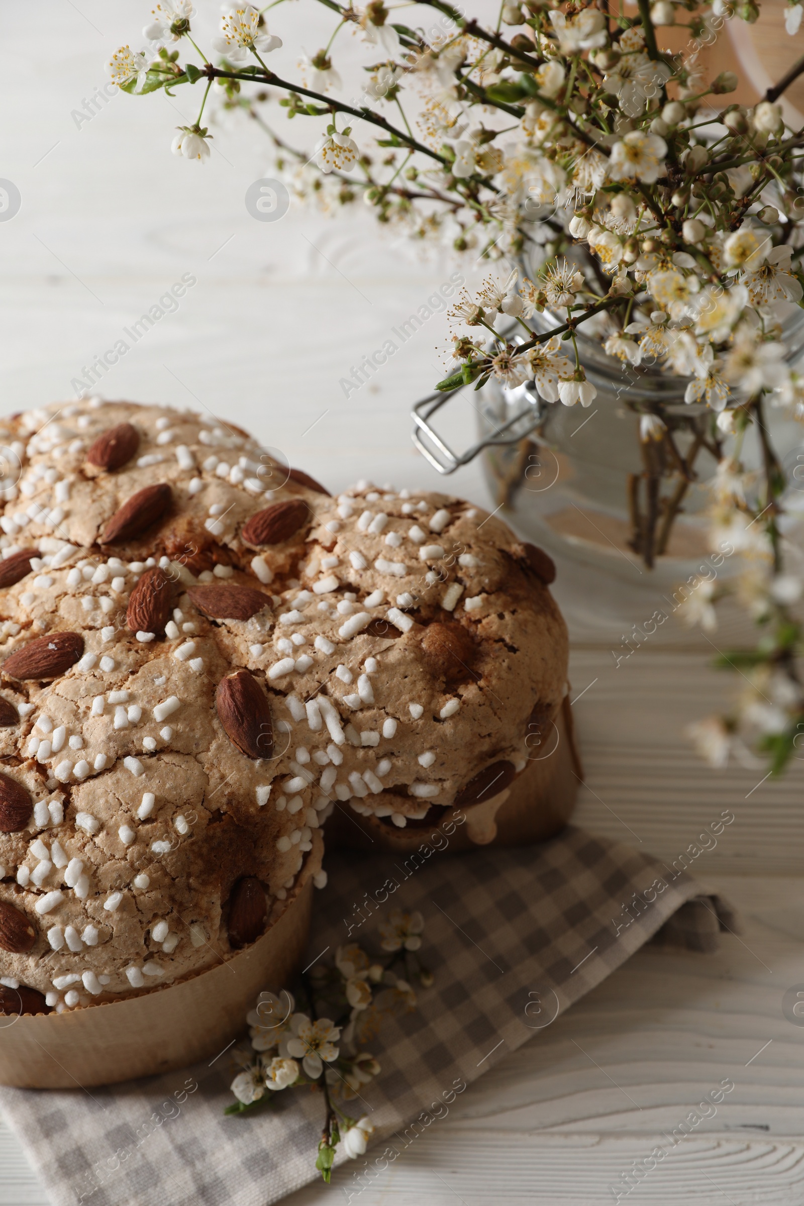 Photo of Delicious Italian Easter dove cake (Colomba di Pasqua) and flowers on white wooden table