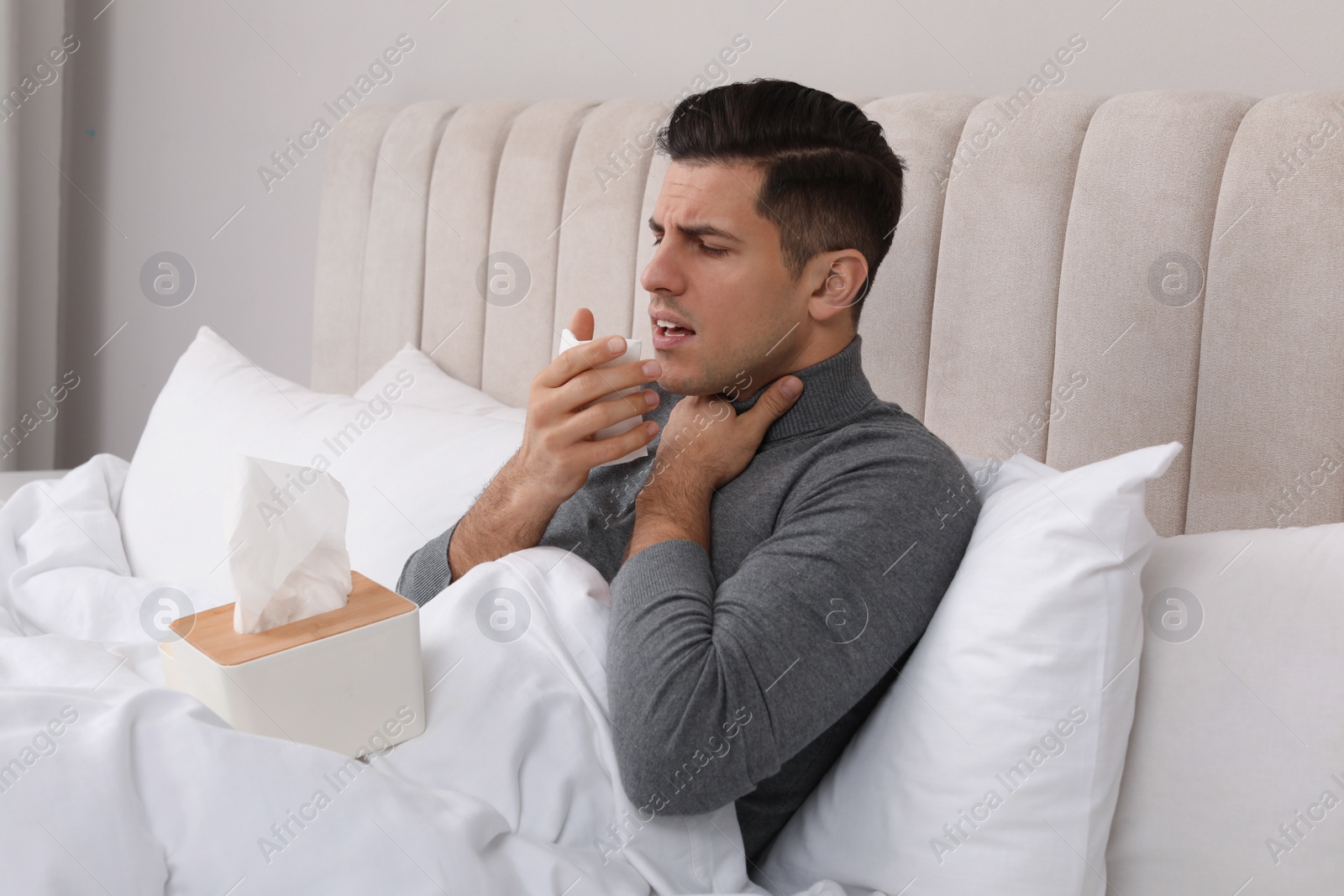 Photo of Sick man with box of paper tissues suffering from cold in bed at home