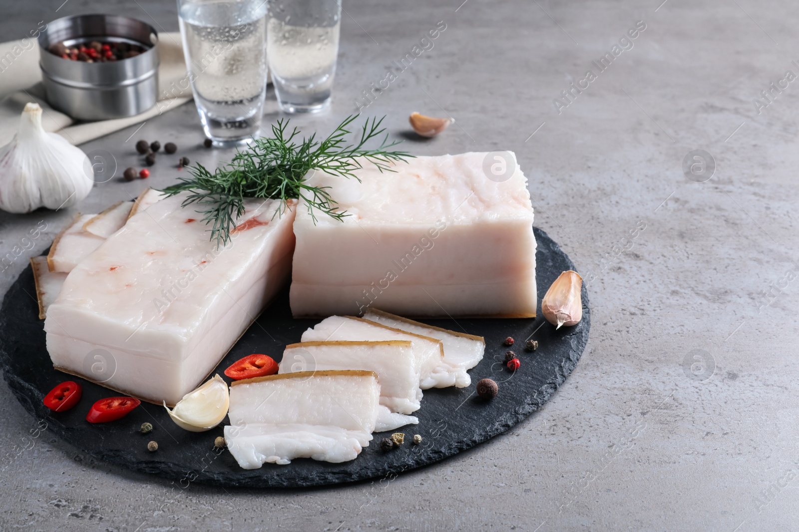 Photo of Pork fatback with spices served on grey table. Space for text