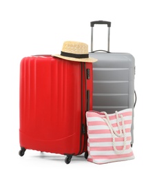 Packed suitcase with hat and hand-luggage on white background