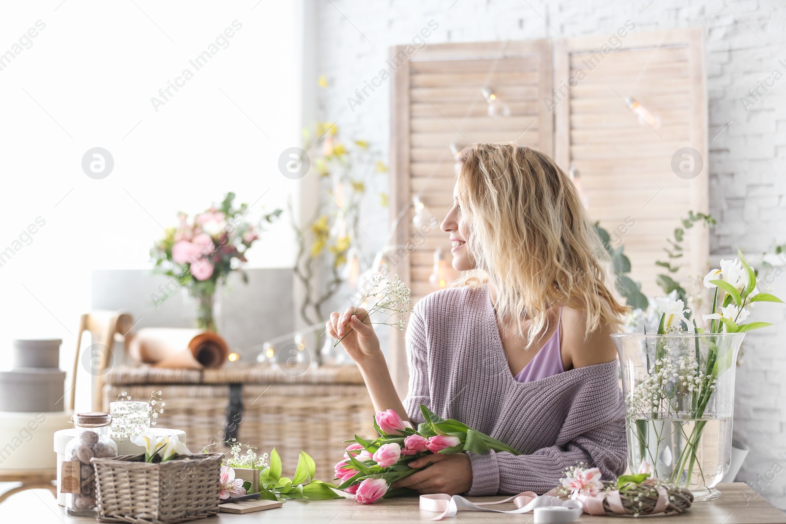 Photo of Female decorator creating beautiful bouquet at table