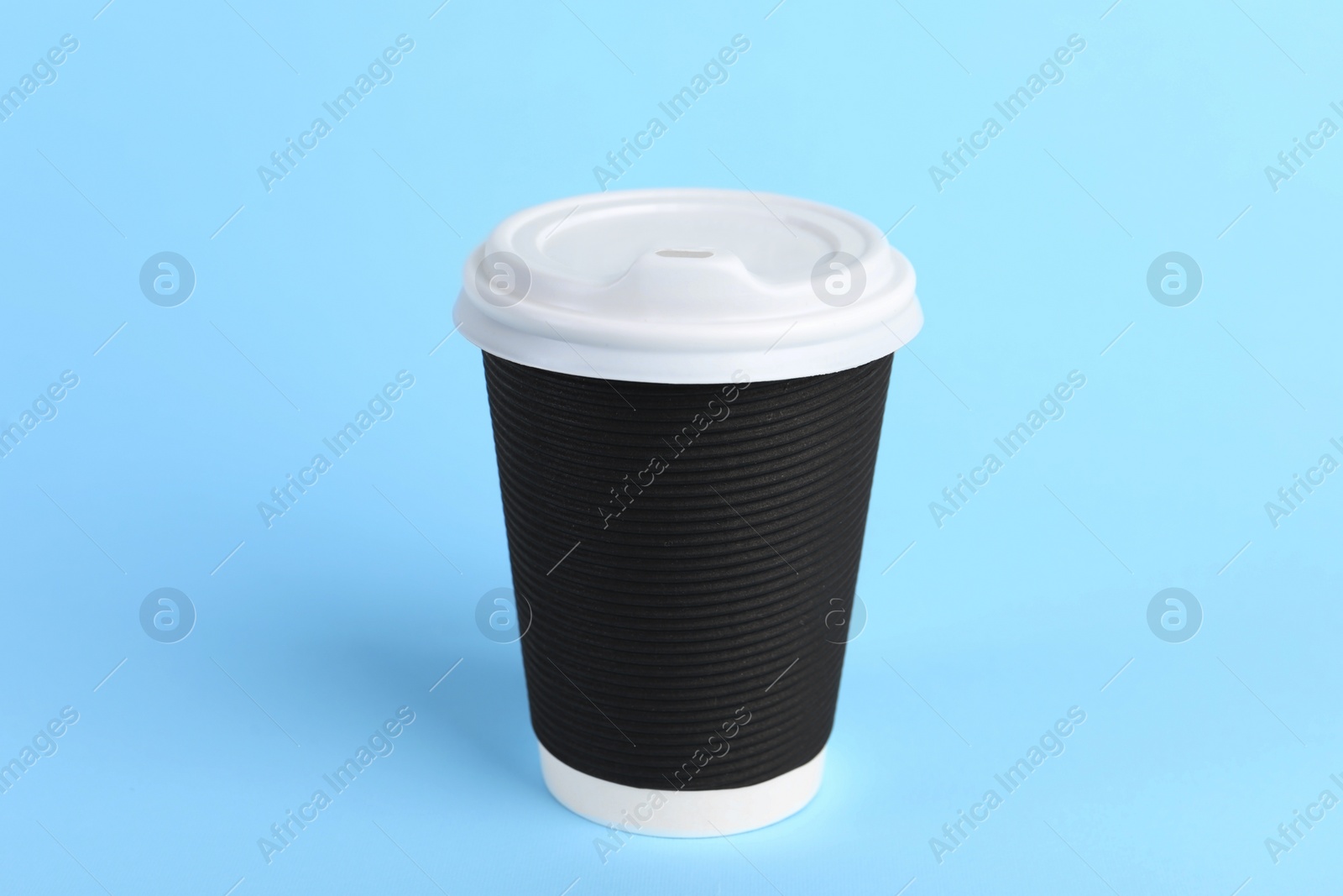 Photo of Black paper cup with plastic lid on light blue background. Coffee to go