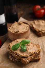 Photo of Fresh bread with delicious meat pate and basil served on wooden table, closeup