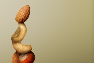 Image of Stacked different nuts on light brown gradient background, space for text