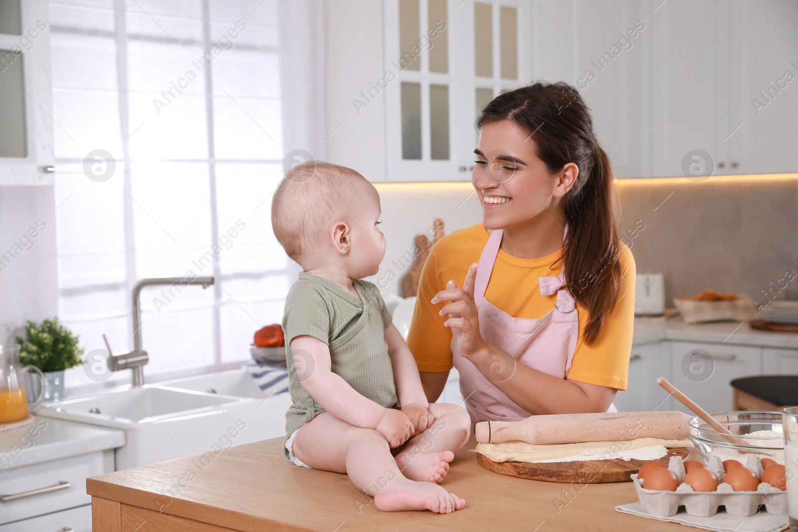 Photo of Happy young woman and her cute little baby cooking together in kitchen