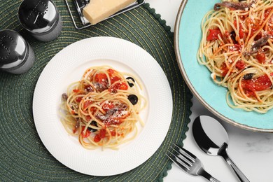 Photo of Delicious pasta with anchovies, tomatoes and parmesan cheese served on white table, flat lay