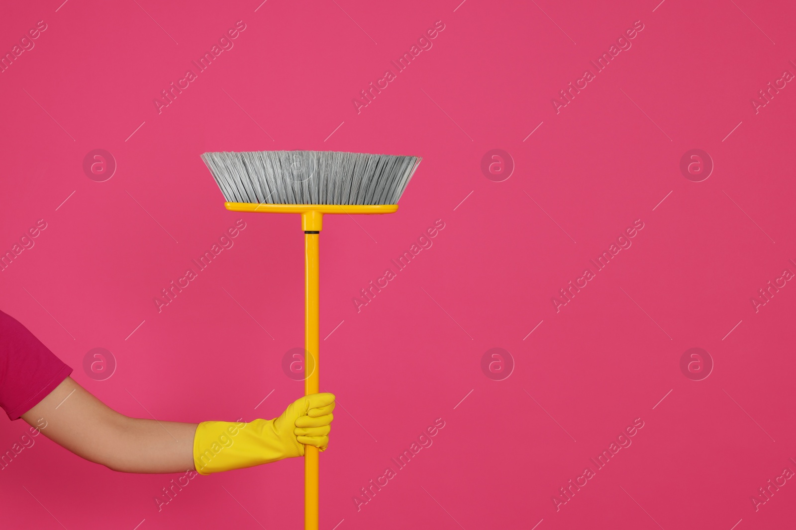 Photo of Woman holding broom on pink background, closeup. Space for text