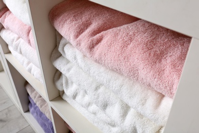 Photo of Colorful towels on shelves, closeup. Bathroom supplies