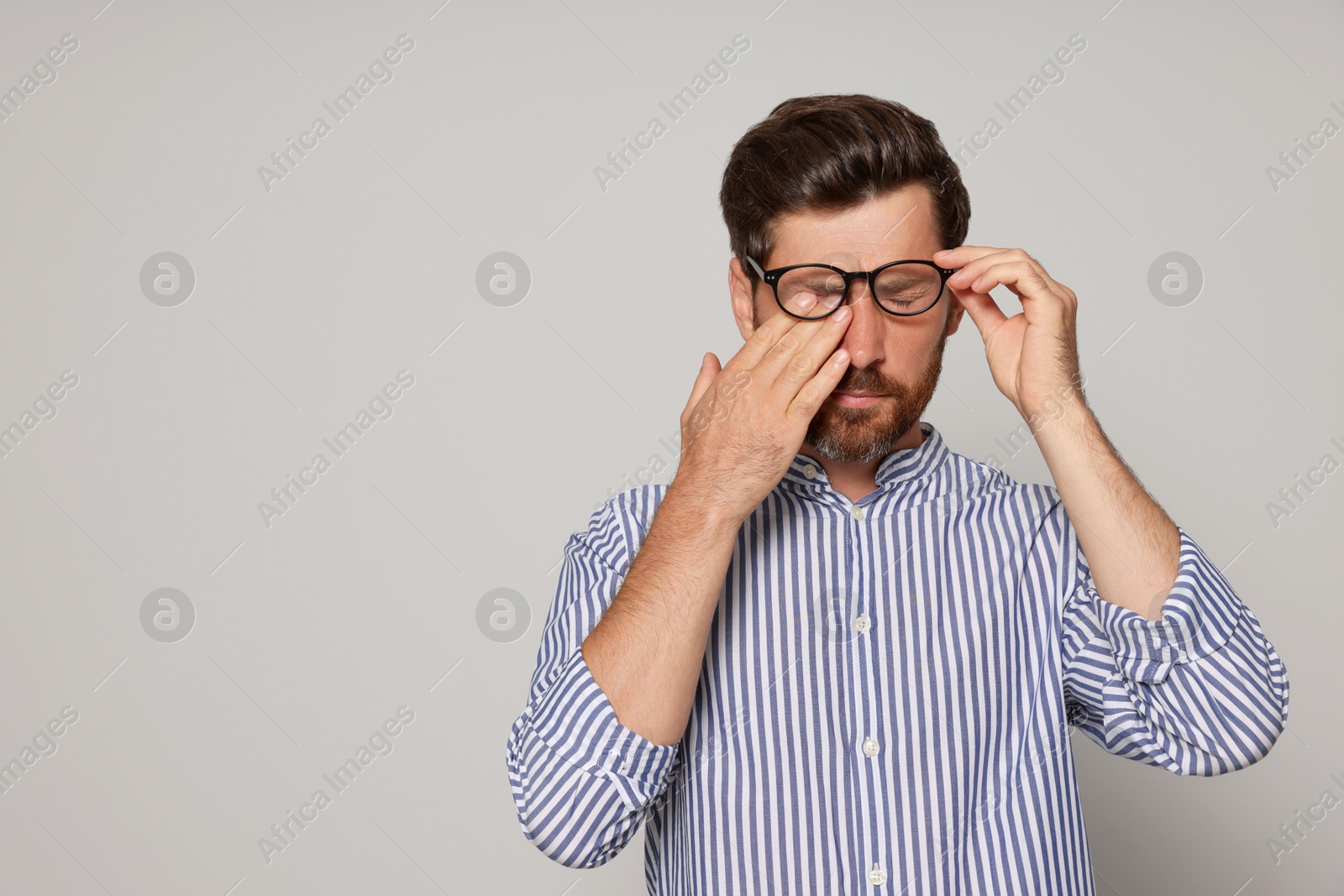 Photo of Man suffering from eyestrain on light grey background. Space for text