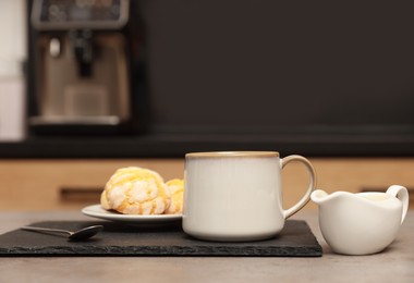 Photo of Cup of coffee, milk and cookies on table in kitchen