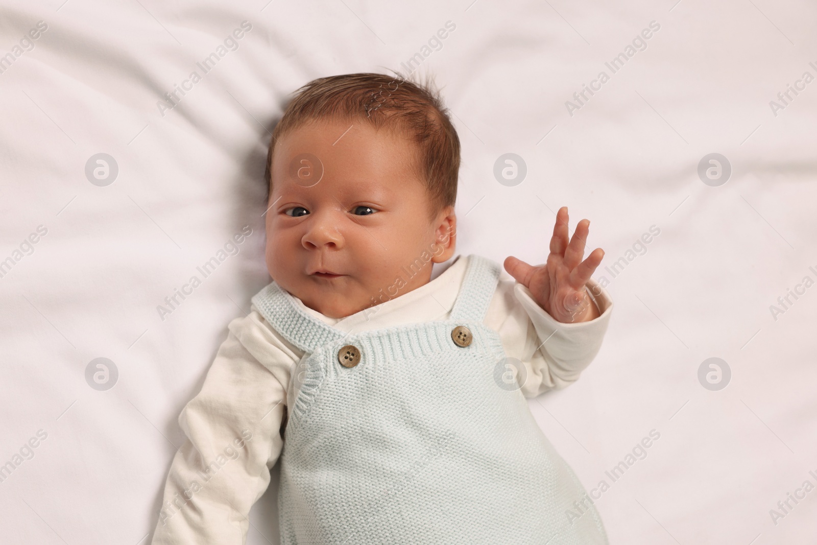 Photo of Cute newborn baby lying on white blanket, top view