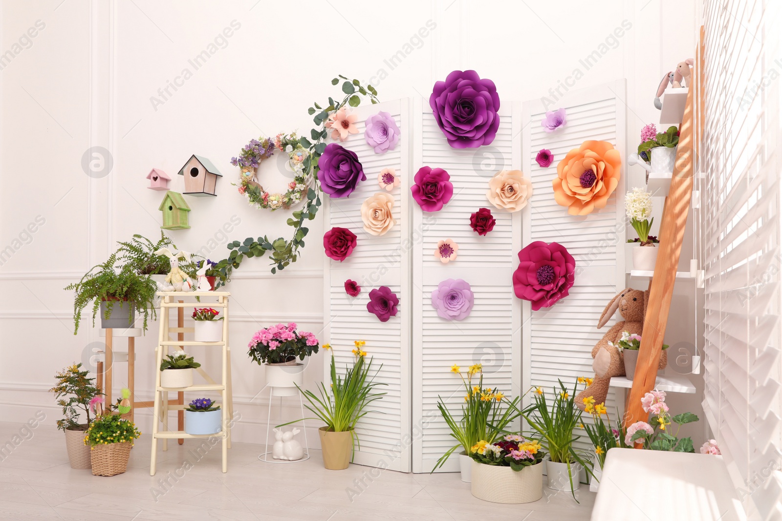 Photo of Easter photo zone with plants and paper flowers indoors