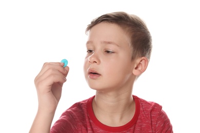 Photo of Little child taking pill on white background. Danger of medicament intoxication