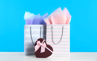Photo of Gift bags and box on white table against light blue background
