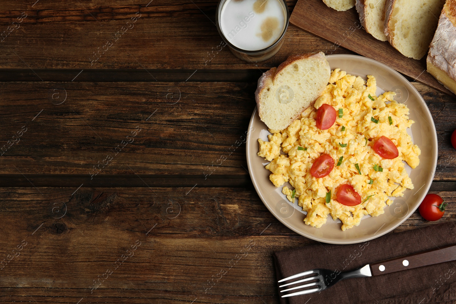 Photo of Tasty scrambled eggs served on wooden table, flat lay. Space for text