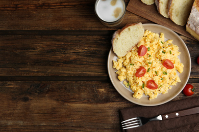 Tasty scrambled eggs served on wooden table, flat lay. Space for text