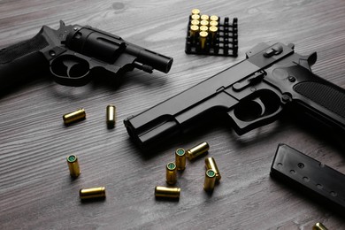 Photo of Pistols and bullets on wooden table. Professional guns