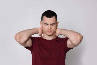 Photo of Man suffering from pain in his neck on light background. Arthritis symptoms