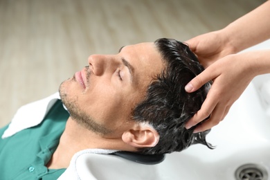 Stylist washing client's hair at sink in beauty salon