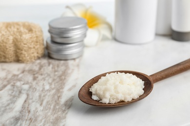 Spoon with Shea butter on marble table, closeup