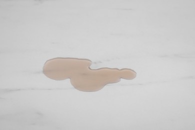 Photo of Puddle of liquid on white marble table, top view