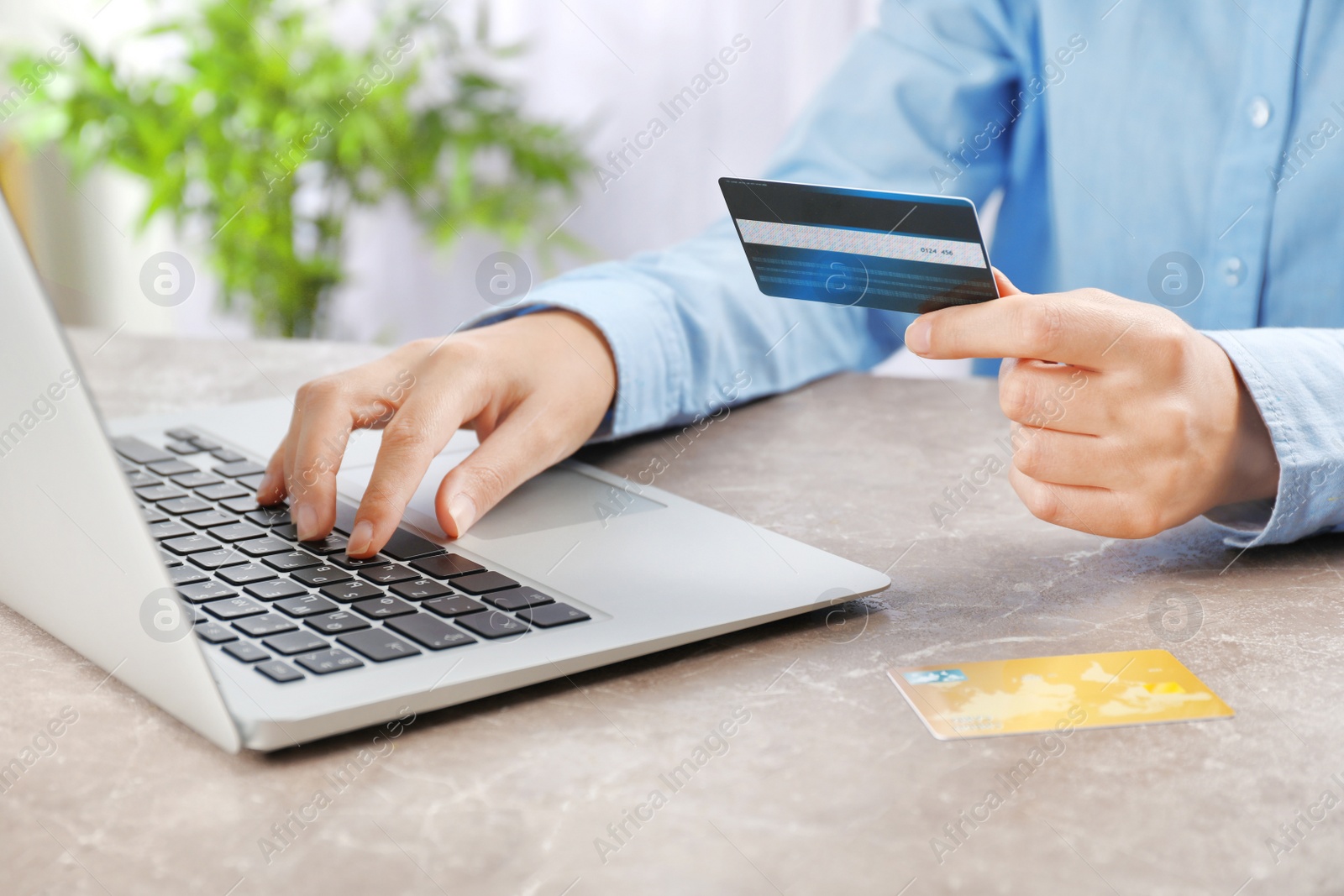 Photo of Young woman with credit card using laptop at table