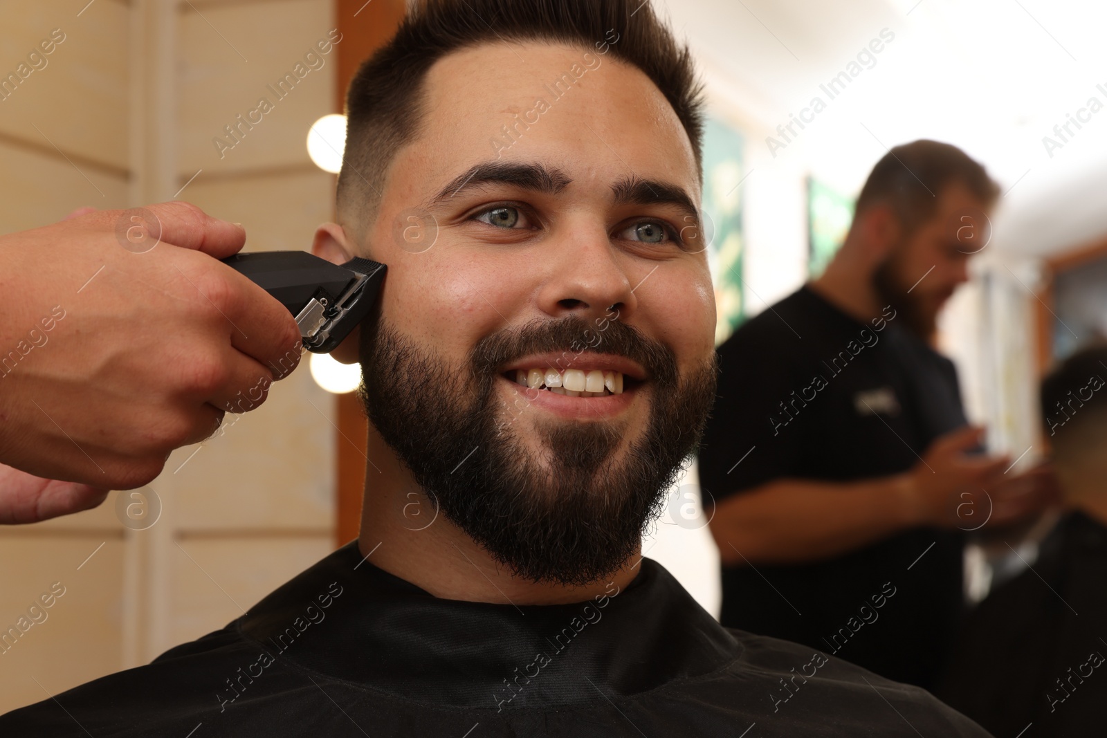 Photo of Professional hairdresser working with client in barbershop, closeup