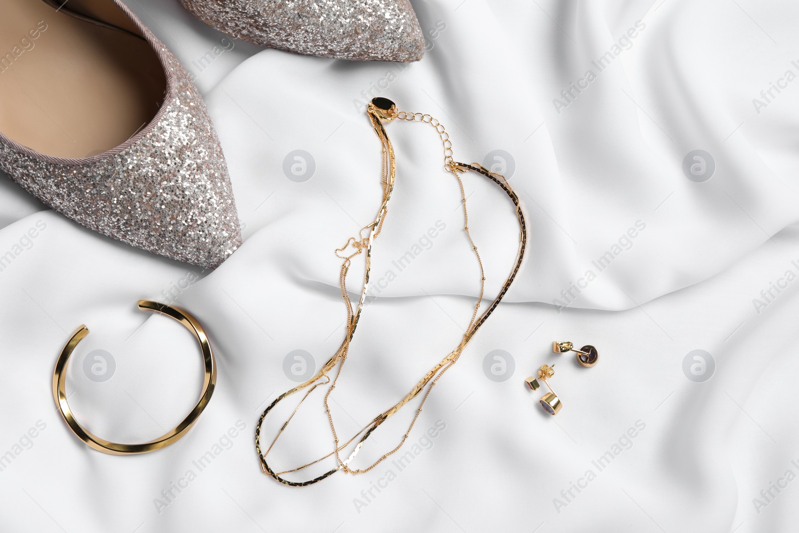 Photo of Flat lay composition with elegant bijouterie on white cloth