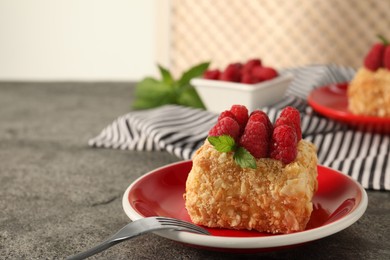 Photo of Piece of delicious Napoleon cake with fresh raspberries served on grey table, closeup. Space for text