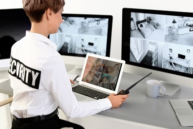 Photo of Female security guard with portable transmitter monitoring home cameras indoors