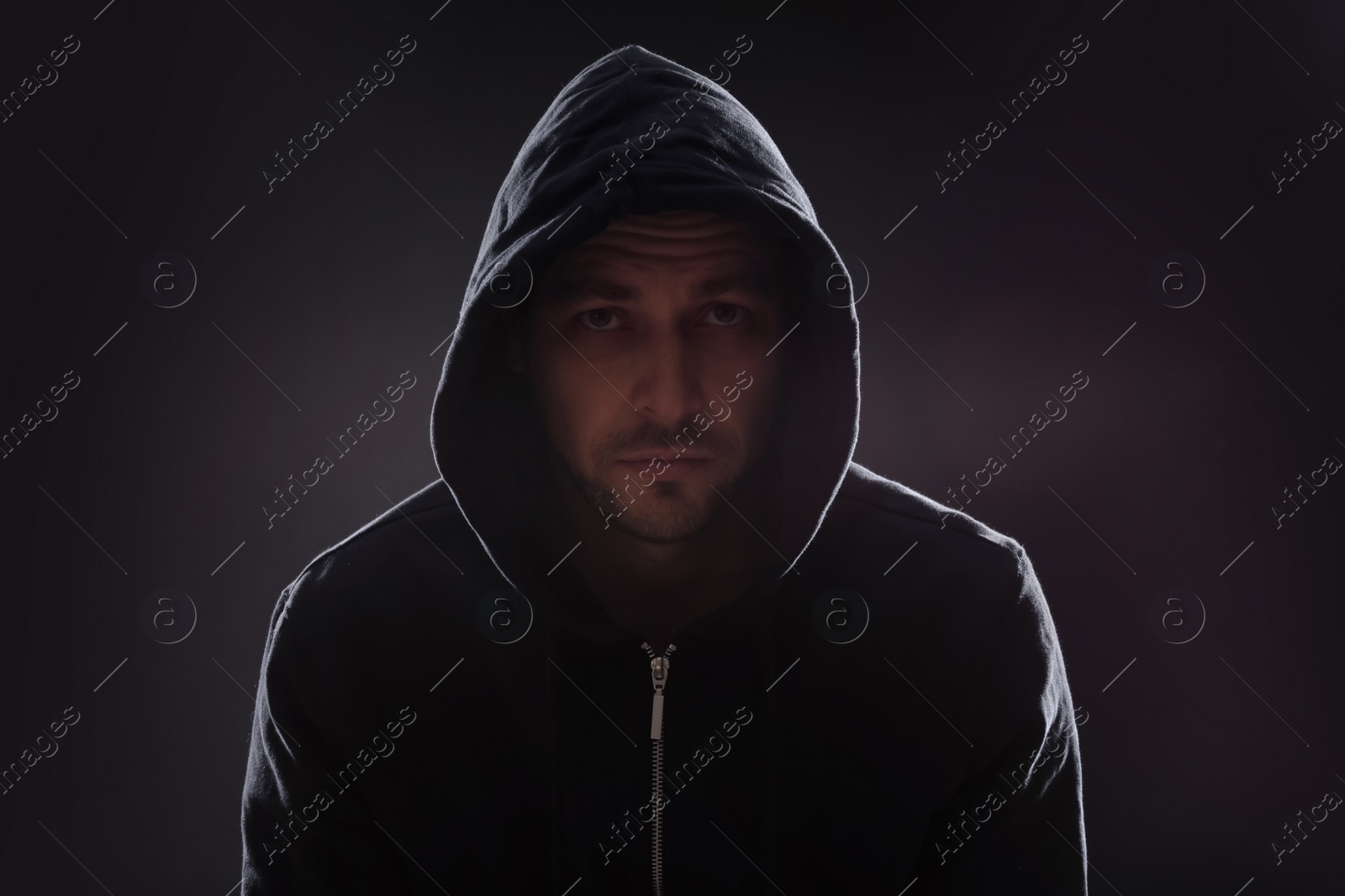 Photo of Mysterious man in hoodie on dark background. Dangerous criminal