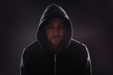 Photo of Mysterious man in hoodie on dark background. Dangerous criminal