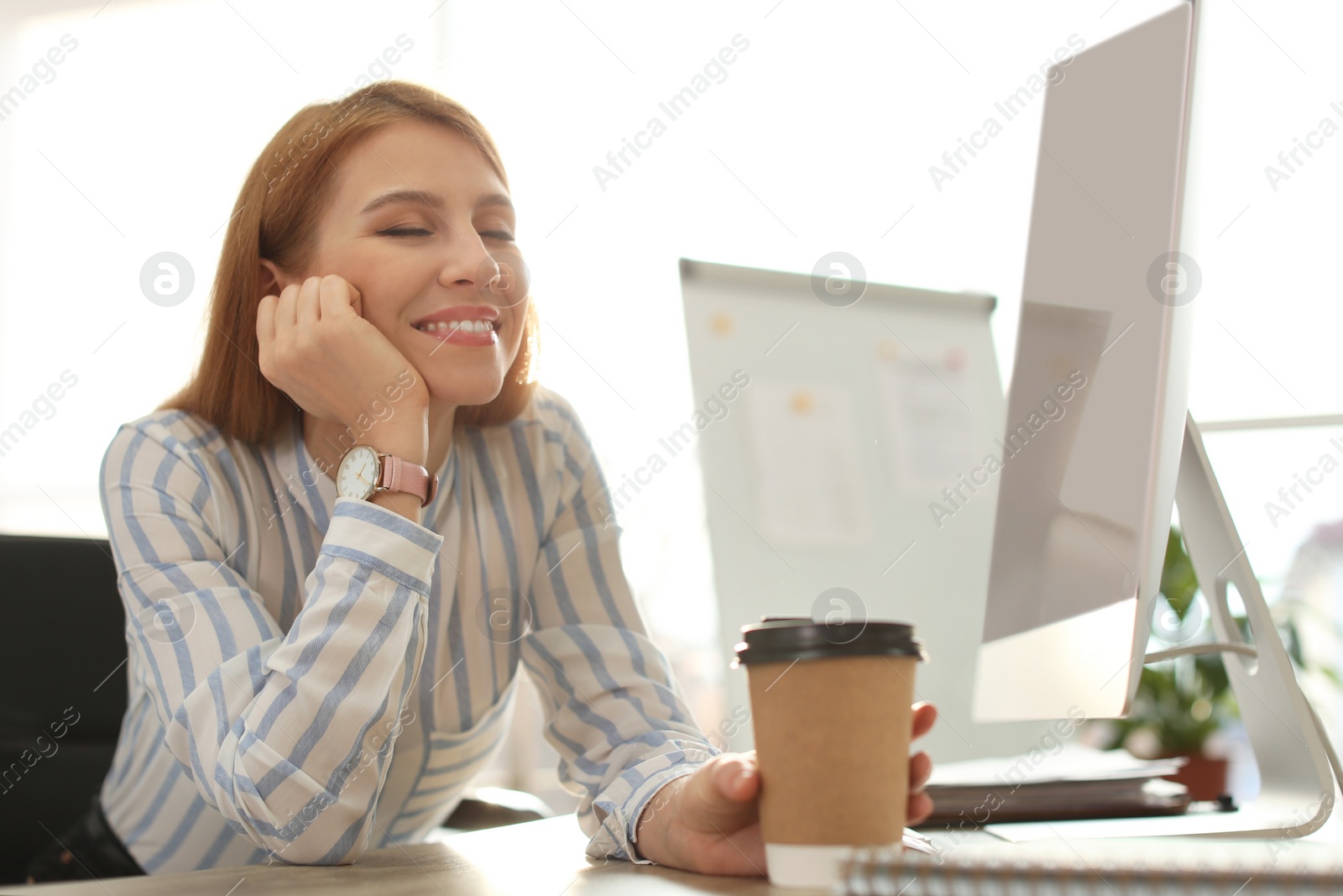 Photo of Young businesswoman with cup of coffee relaxing at table in office during break