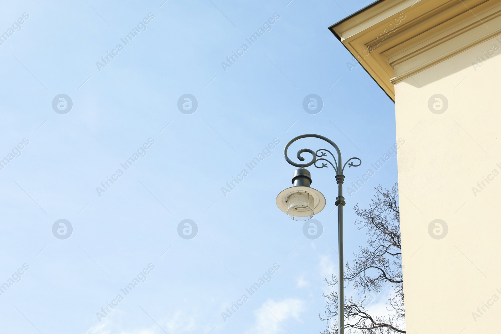 Photo of Old fashioned street light lamp near building against cloudy sky
