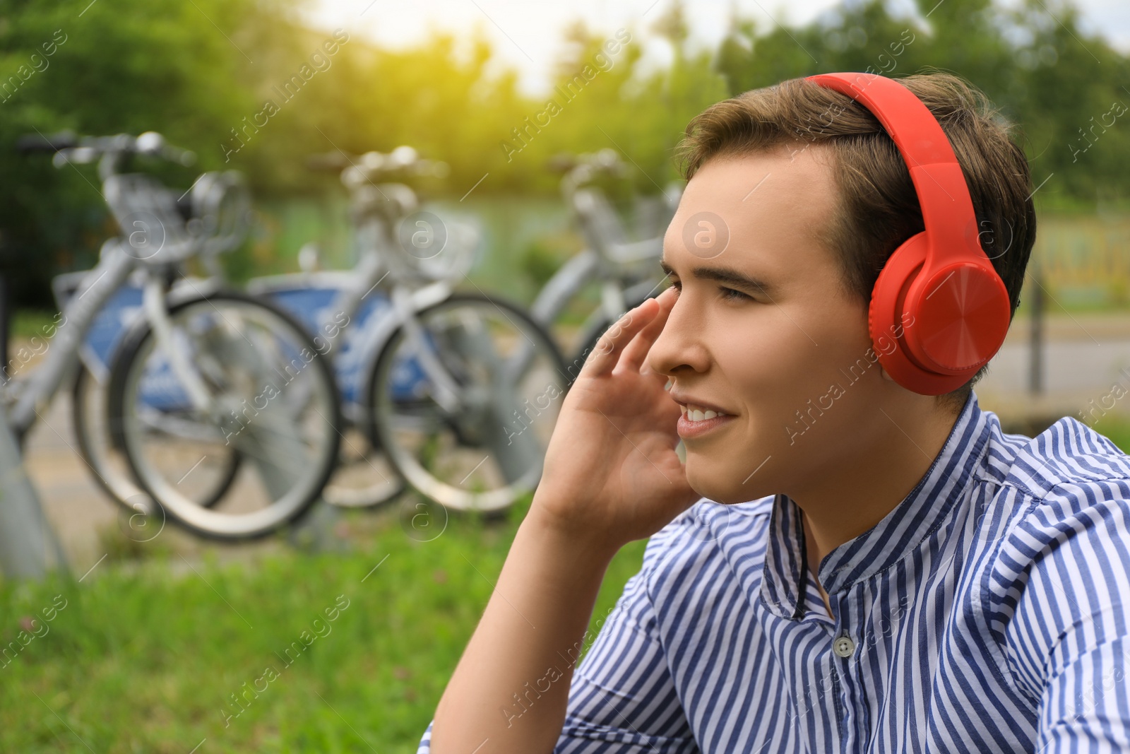 Photo of Handsome young man with headphones outdoors on sunny day